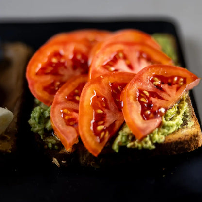 Fresh avocado toast with sliced tomatoes and seasoning available for online pickup and delivery from Fresh Juiced Juice Bar in Redlands, California
