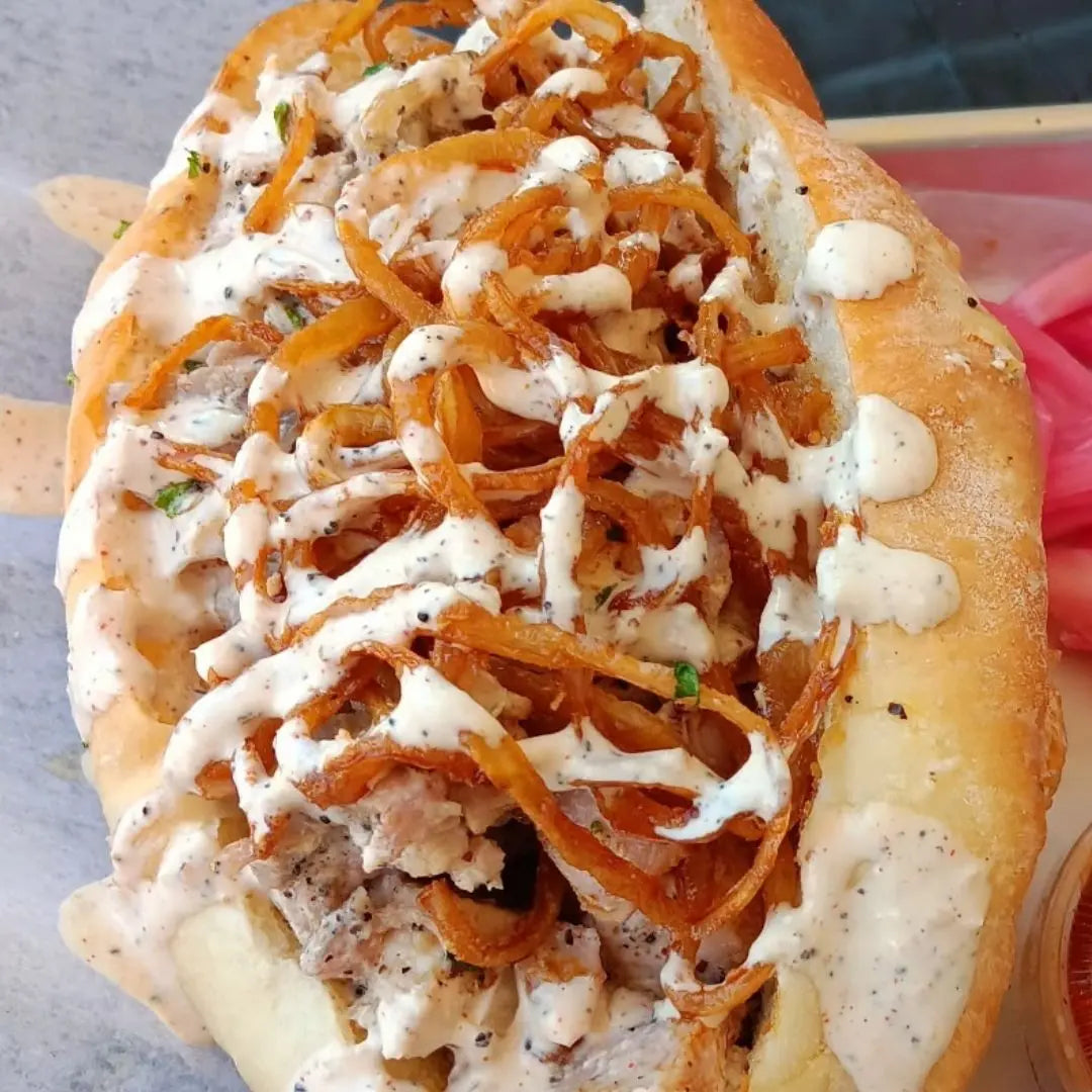 Alabama white sauce pulled chicken sandwich with crispy fried onions on a soft roll available for online pickup and delivery from Hoodidya BBQ in Redlands, California
