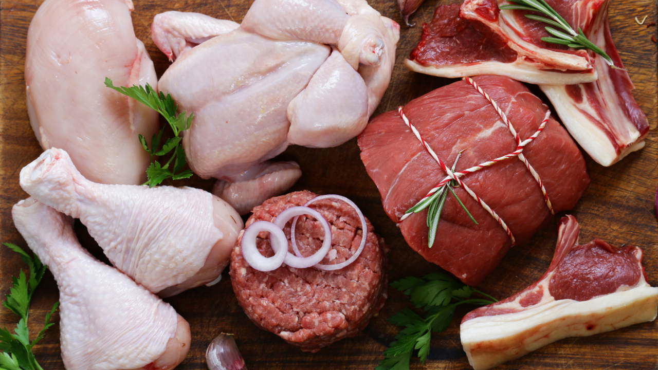 A wooden board contains a variety of meat cuts, including chicken legs, chicken breast, whole chicken, hamburger patties, roast, steak, etc. 